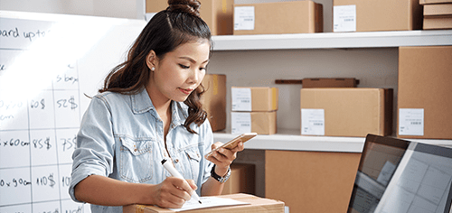auction-and-price-streaming.png Young entrepreneur checking inventory on smartphone in a small business warehouse.