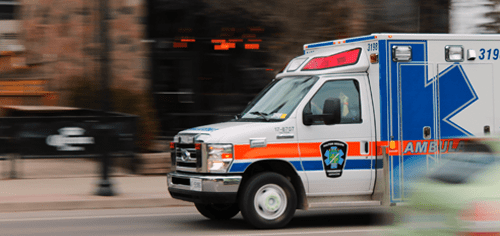 Blurred background with a moving ambulance in focus on a city street.