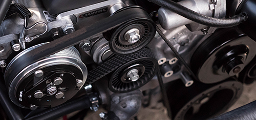 Close-up of a car engine showing detailed belts and pulleys systems.