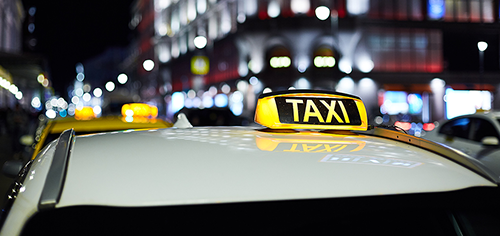 Get inspired taxi Illuminated taxi sign on top of a cab at night with blurred city lights in the background.