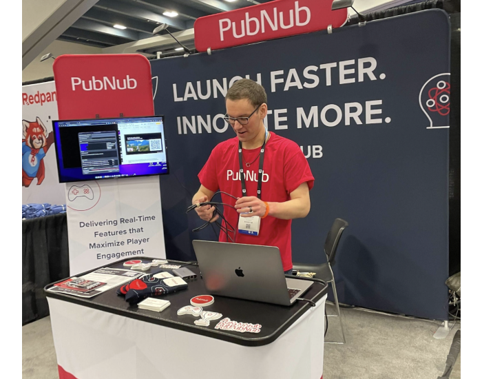Oliver, a PubNub employee wearing a PubNub T-shirt in front of the PubNub booth at GDC 2024